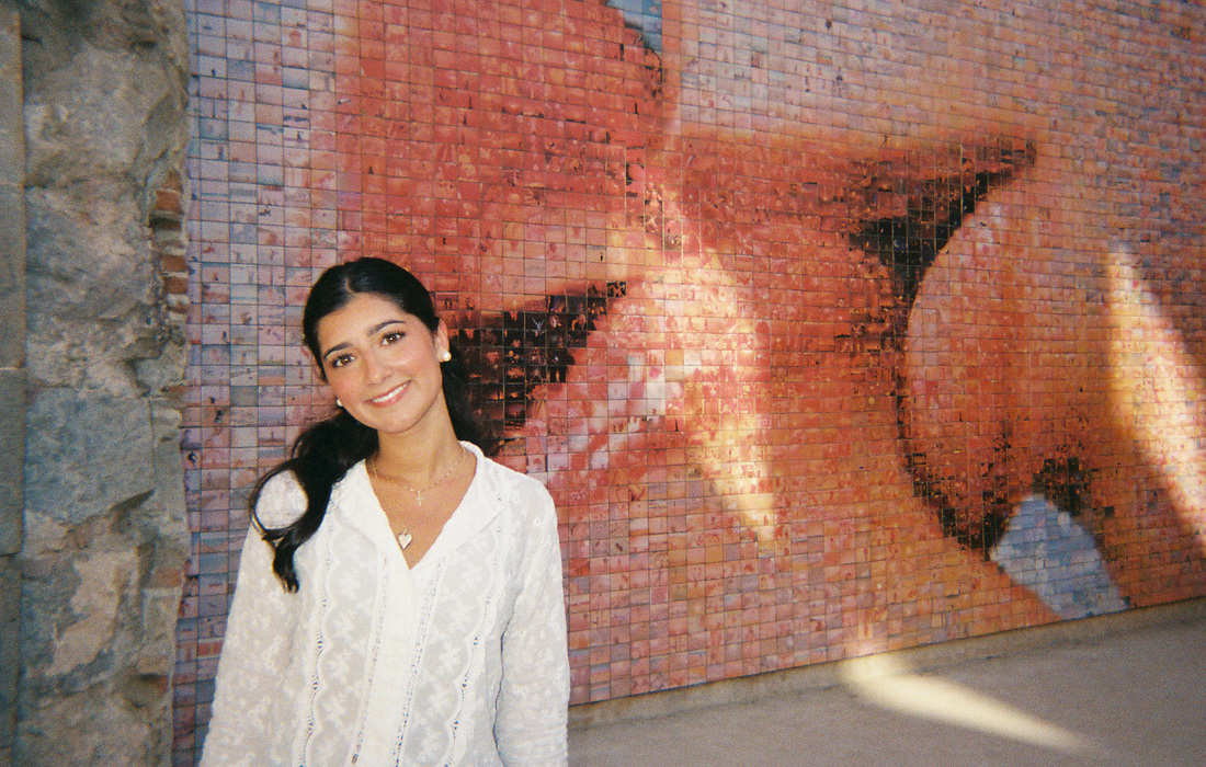 Olivia Emma Koleszar in front of a tiled mural